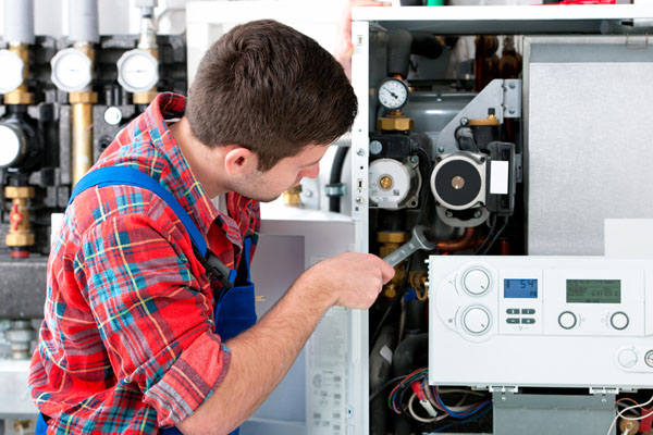 HVAC technician inspecting and repairing boiler controls in Tucson